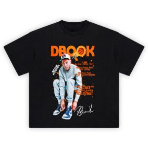 Devin Booker Medal Mindset tee featuring DBook seated in USA hat, career highlights in orange text, Jordan sneakers, and bold "DBOOK" title