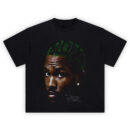 Blond Big Face Tee graphic showing a close-up portrait with green hair featuring the word “BLOND,” a stud earring, and a signature-style detail on a black tee.