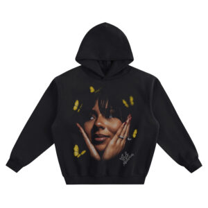 Mariah the Scientist Big Face Hoodie graphic showing a close-up portrait with hands framing the face, red nails, yellow butterflies, and signature detail on a black hoodie.