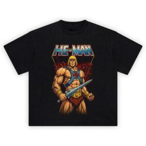He-Man Graphic Tee graphic showing the “HE-MAN” title above He-Man holding a sword, wearing a blue chest harness with red emblem, gold belt, and red rocky background on a black t-shirt.