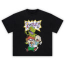 Rugrats Graphic Tee graphic showing a purple “Rugrats” logo in a white starburst with yellow outline above Reptar with open mouth, plus Tommy holding a bottle and Chuckie with purple glasses on a black tee.